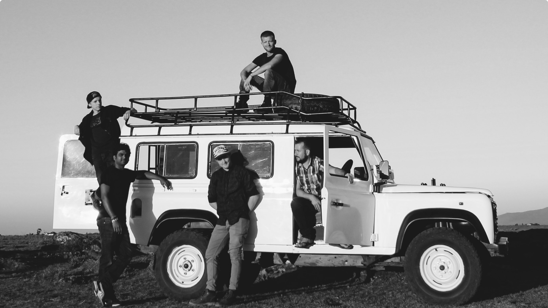 Black and white photograph of friends sitting on a Land Rover for the article How to Build Great Friendships that Thrive