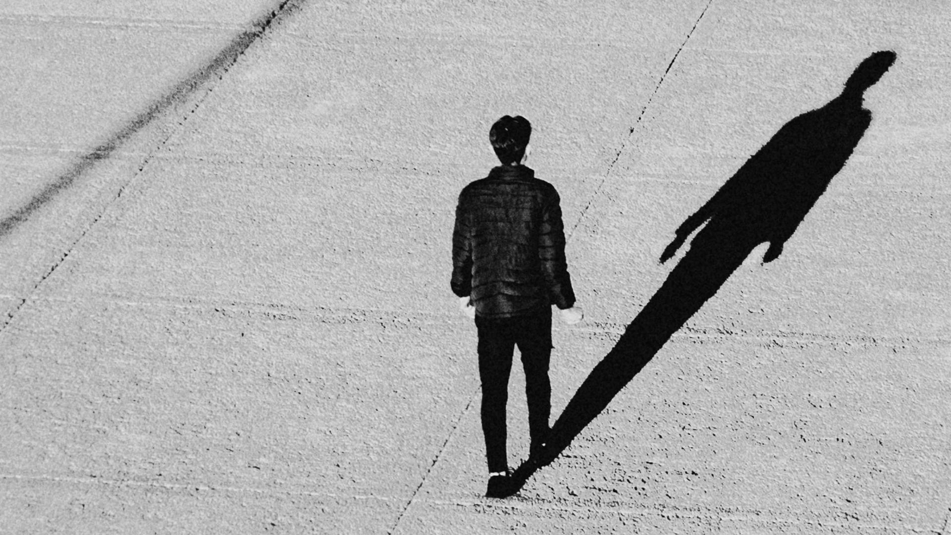 Photograph of a man walking, casting a shadow